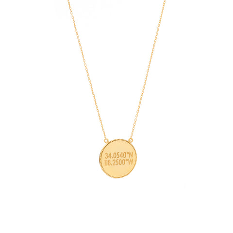 A flat circular gold pendant with inscription with scalloped edges on a gold chain