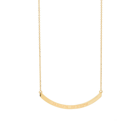 A long gold curved horizontal pendant with inscription on a gold chain